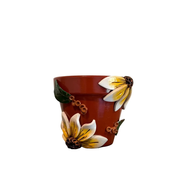 A small terracotta-colored ceramic cup with hand-painted white and yellow flowers and green leaves