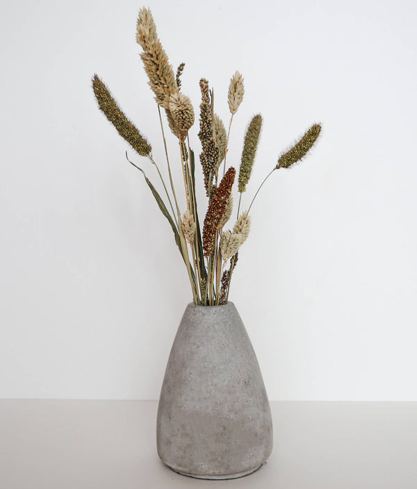 Concrete vase filled with dried plants.