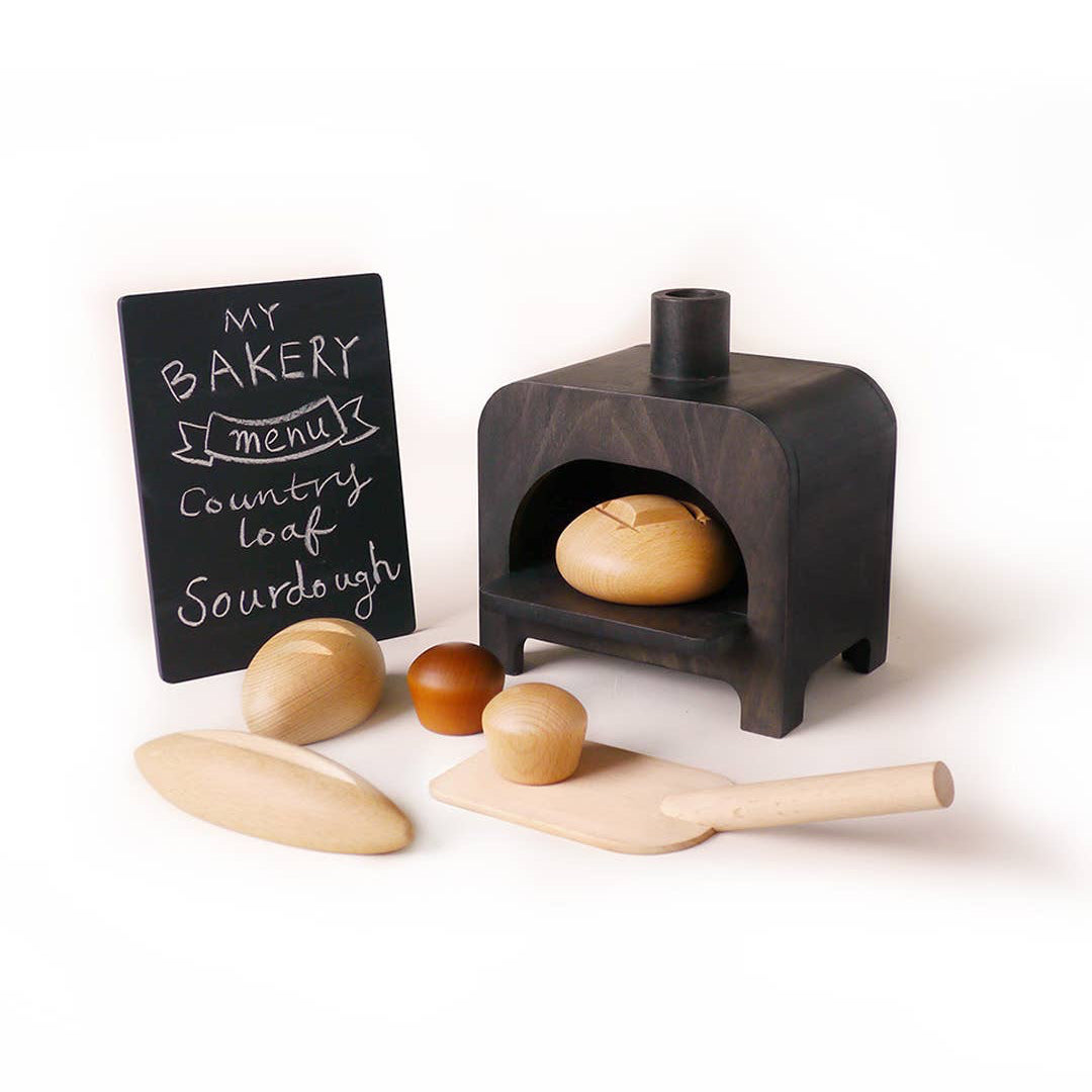 Wooden toy bakery set with oven, loaves of bread, spatula, oven and a chalkboard sign.
