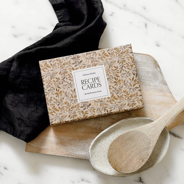 Box of recipe cards on a marble surface with a wooden spoon and black cloth.