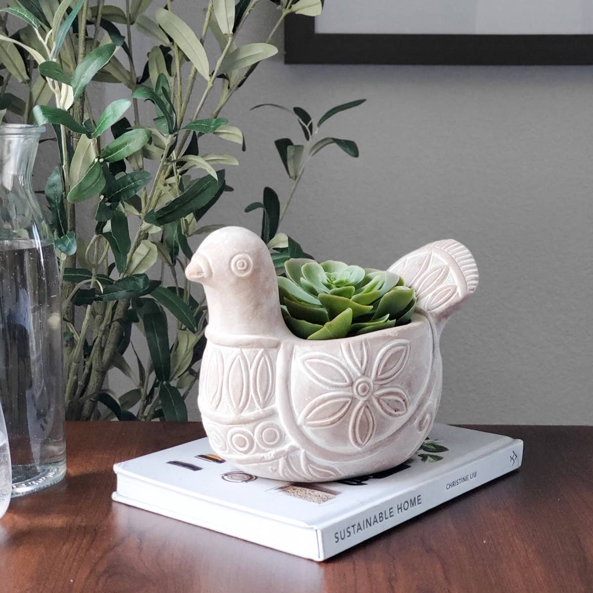 Terracotta bird-shaped pot planted with succulents sitting on a book