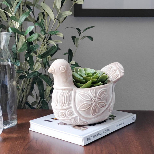 Terracotta bird-shaped pot planted with succulents sitting on a book
