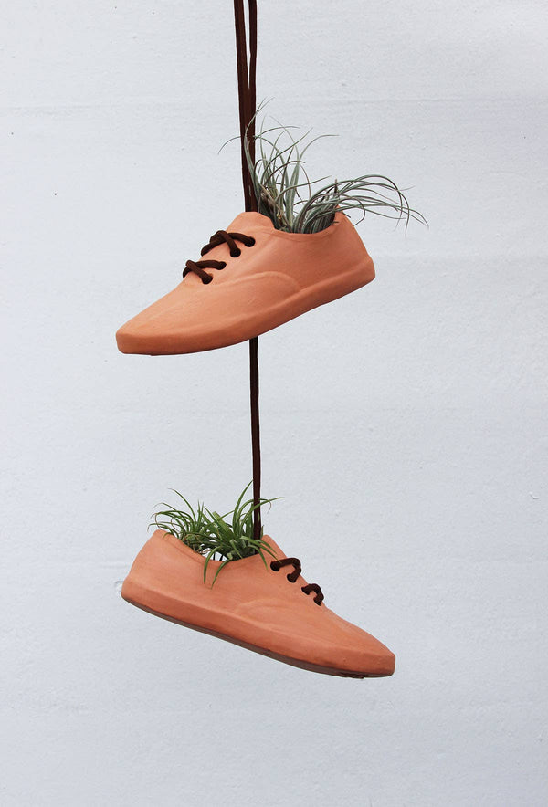 Terracotta shoe planters hanging with plants inside.