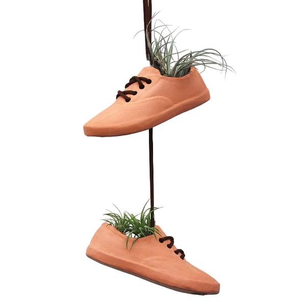 Terracotta shoe pots with plants growing out of them.